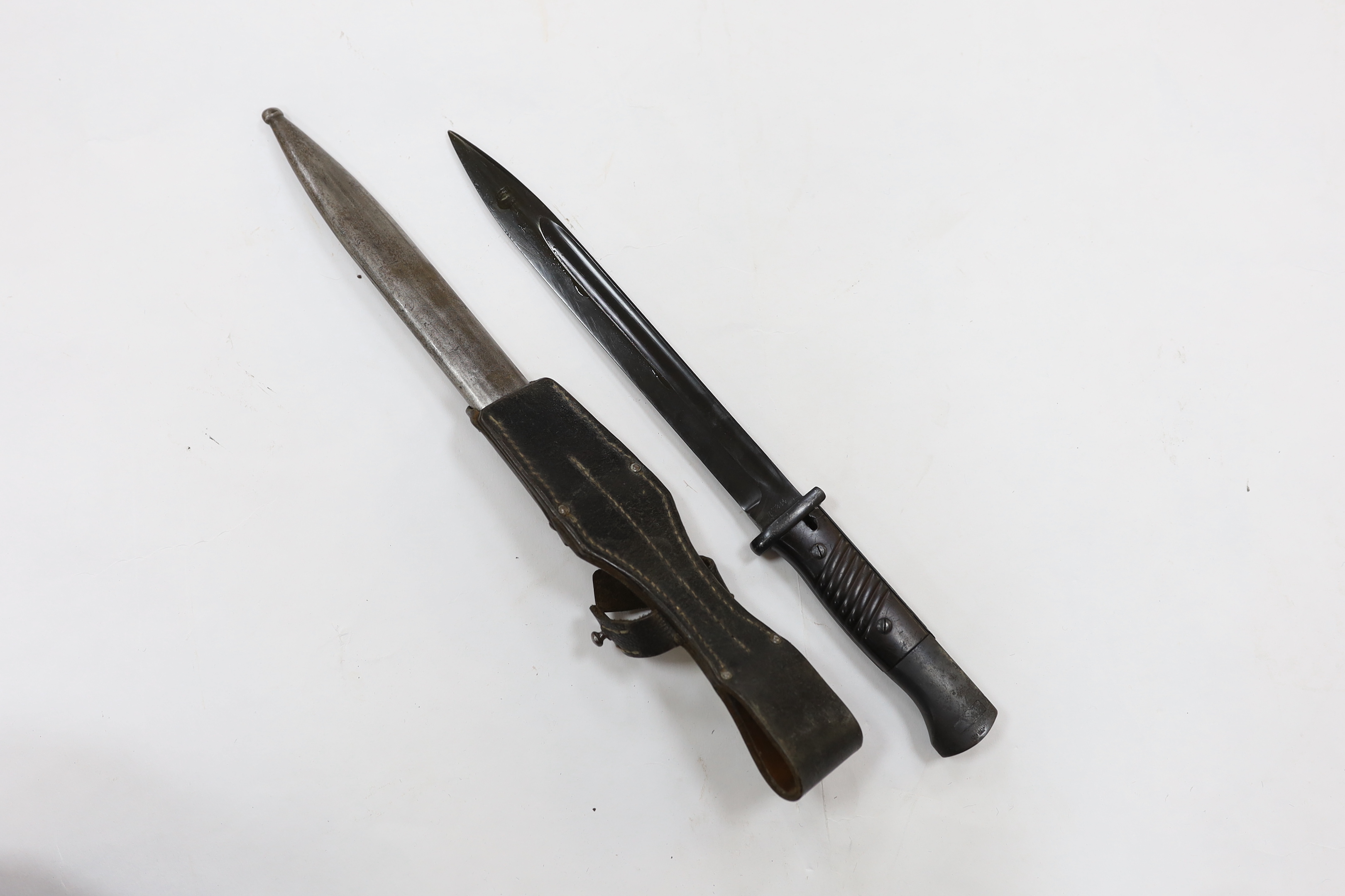 Four bayonets; two Mauser bayonets in scabbards, an American M8A1 carbine bayonet in a scabbard, and another